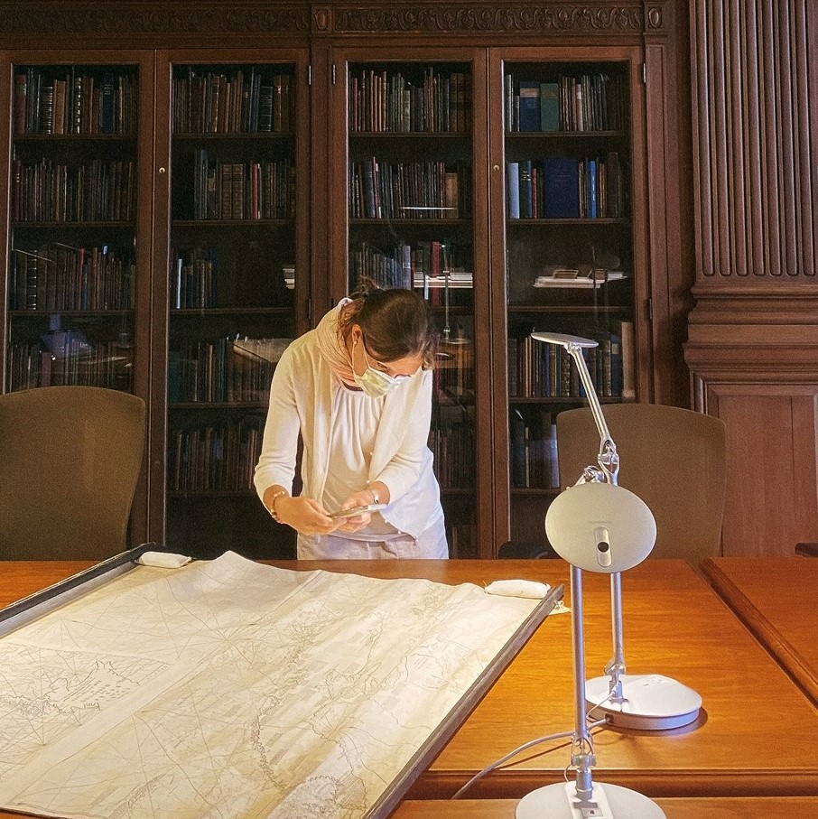 A faculty member standing over a historical map to take a photo